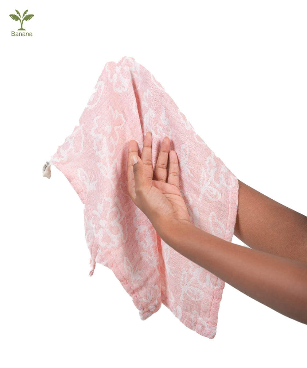 Person holding a pink towel with a white pattern on a white background